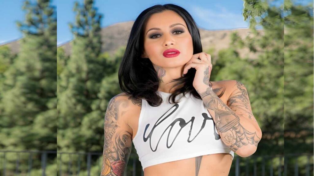 Alby Rydes with tattoos poses confidently for a photo, showcasing her unique body art and style.
