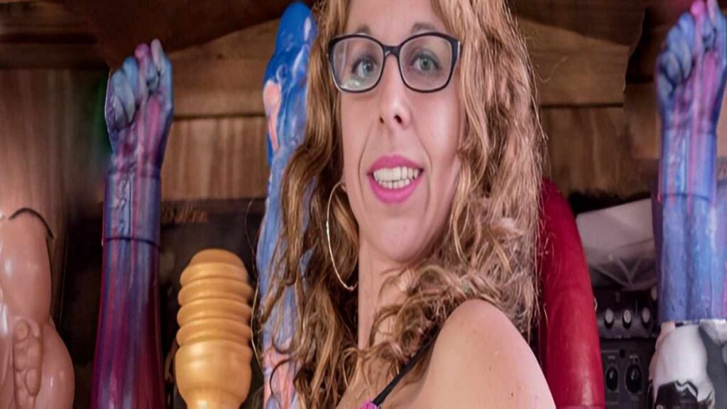 Argendana wearing glasses and a pink top poses for a photo, smiling at the camera.