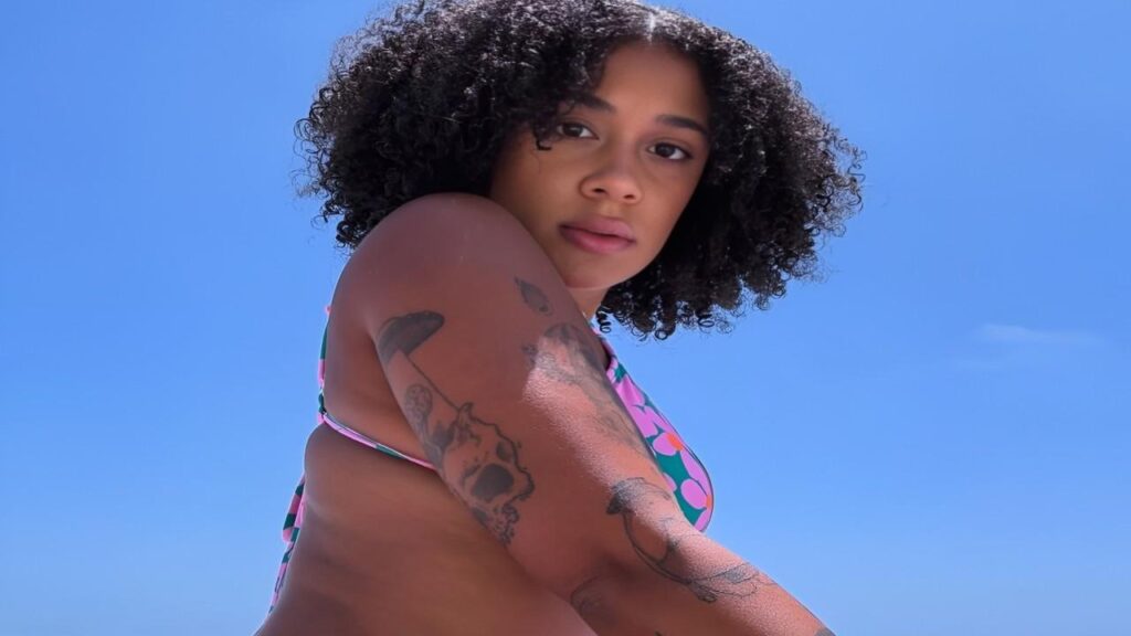 Ariana Aimes with intricate tattoos adorning her arms and legs, showcasing her unique style and personal expression