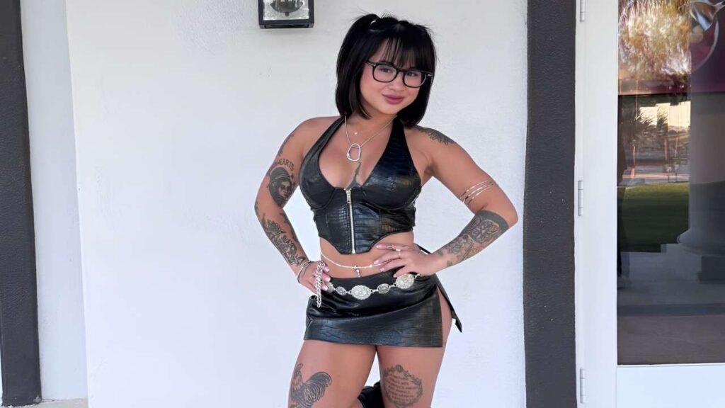 Britney Loh with tattoos wearing a leather skirt, posing confidently against a neutral background