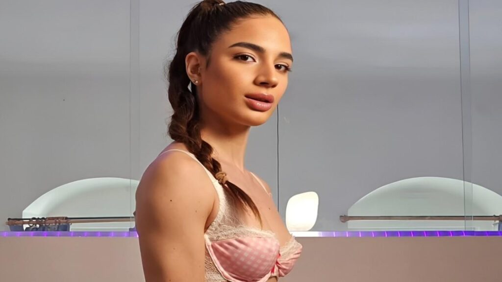 Candie Luciani poses confidently in a pink bra and panties, showcasing a stylish lingerie set.