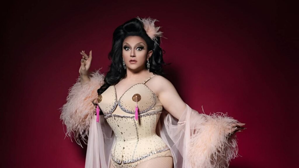 Dita Von Teese poses confidently in a corset adorned with feathers, showcasing a bold and artistic fashion statement