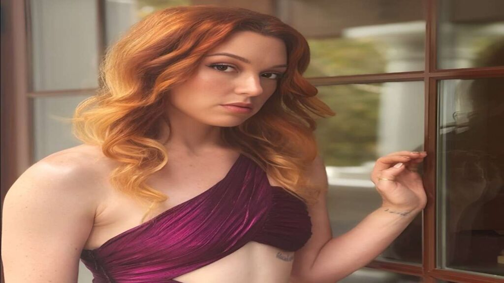 Jennifer Stone with red hair wearing a purple dress stands confidently, showcasing her vibrant style