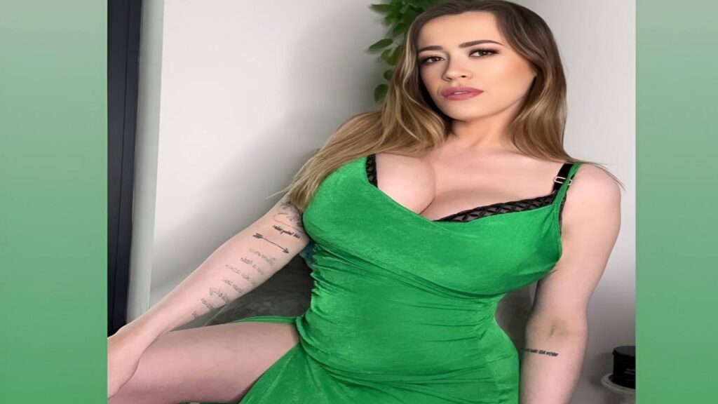 Leanne Crow in a green dress poses for a photo, smiling and standing confidently against a neutral background