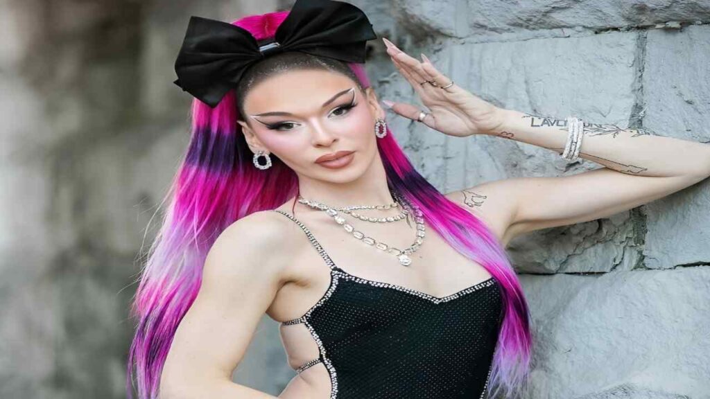 Lexi Love with vibrant pink and purple hair striking a pose, showcasing her colorful hairstyle and confident expression