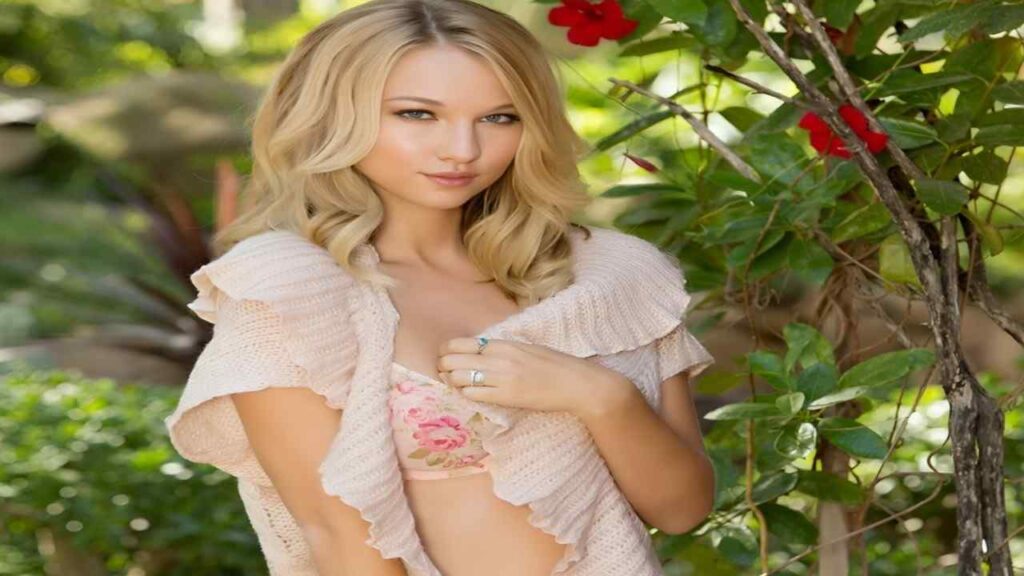 Lily Ivy wearing a pink bikini poses confidently by the water, showcasing her summer style