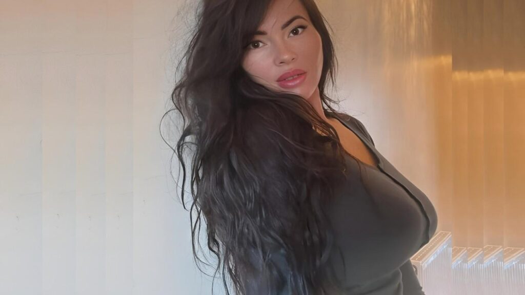 Rachel Aldana with long hair poses for a photo, smiling and looking directly at the camera.