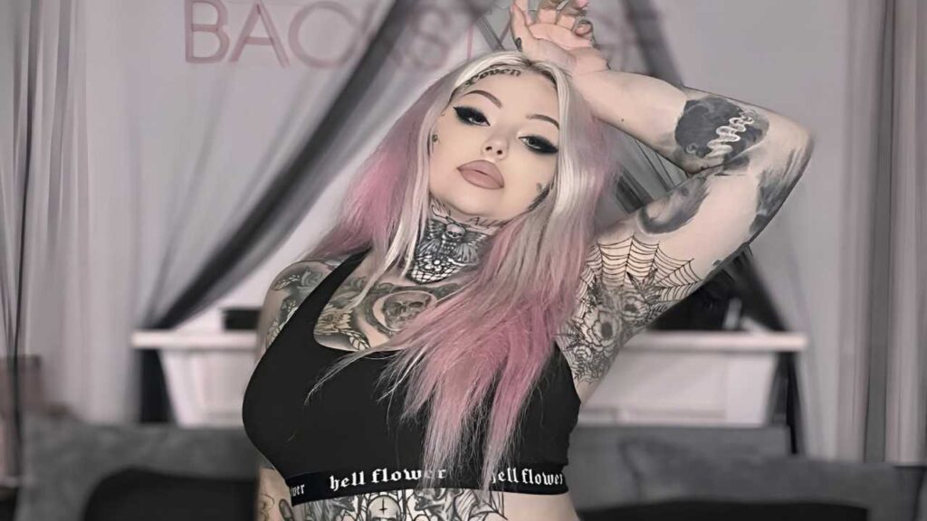 Zoe Melissa with pink hair and tattoos poses confidently, showcasing her unique style and personality