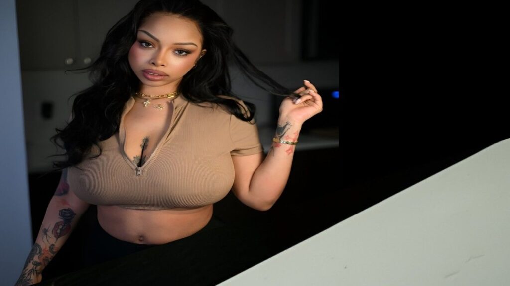 Advoree with tattoos poses confidently, showcasing her unique style and prominent chest