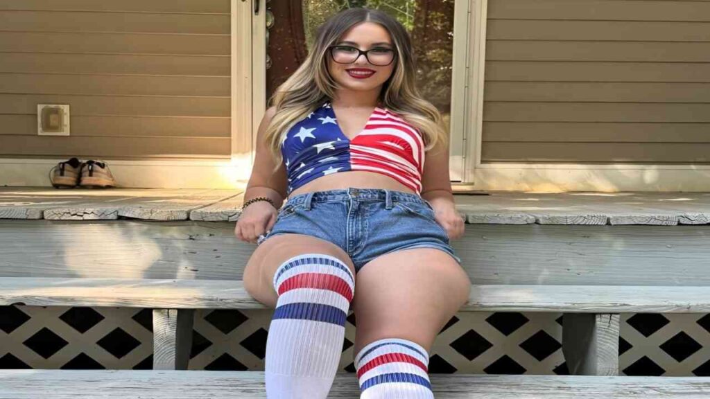 Aria Banks in a patriotic outfit sits on steps, showcasing her pride in her country's colors and symbols