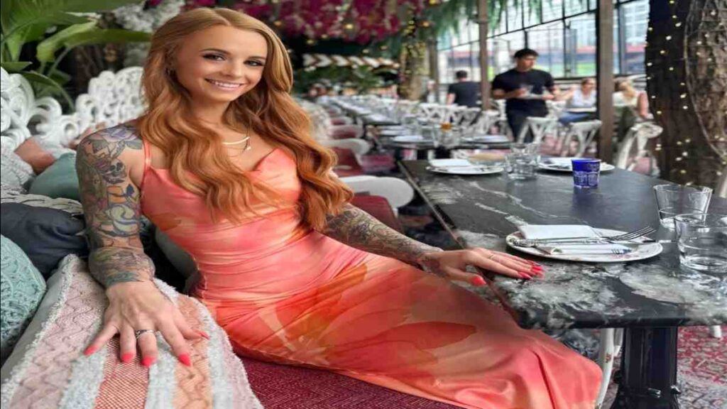 Brea Bennett with tattoos sits at a table, engaged in conversation or contemplation.