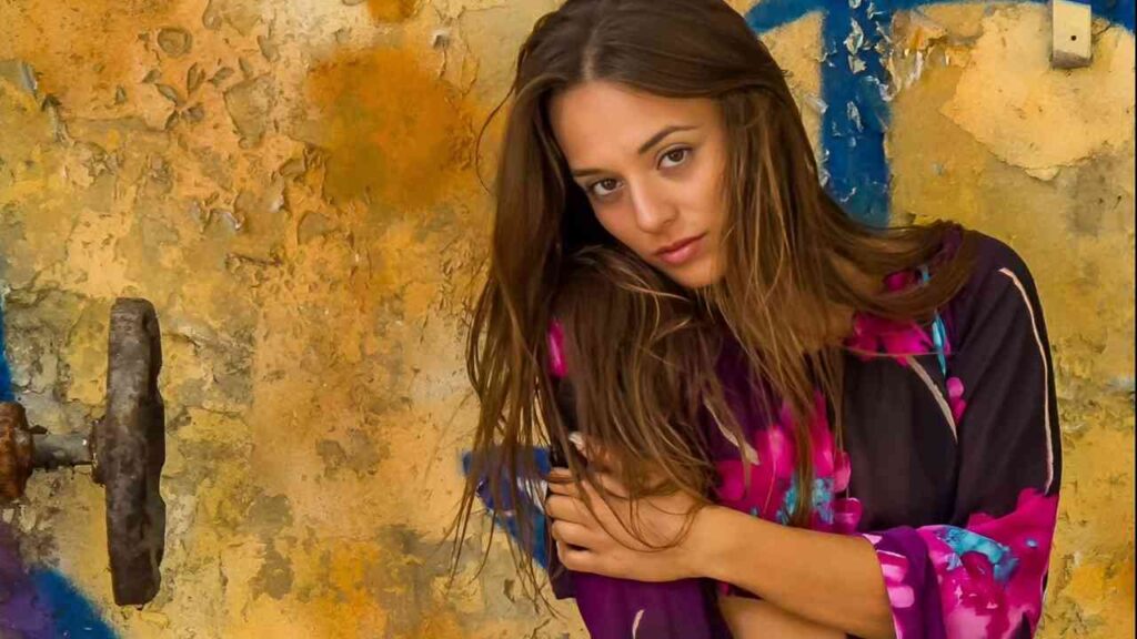 Dominika C leans against a wall adorned with colorful graffiti, showcasing urban art and her casual pose