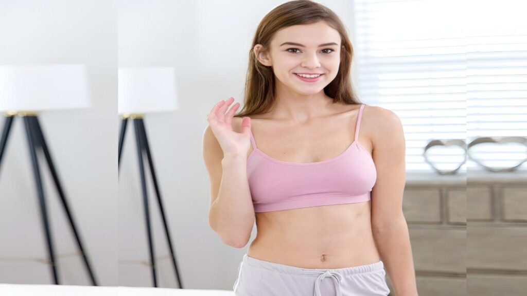 Ellie Eilish wearing a pink bra top and gray shorts stands confidently, showcasing a casual summer outfit