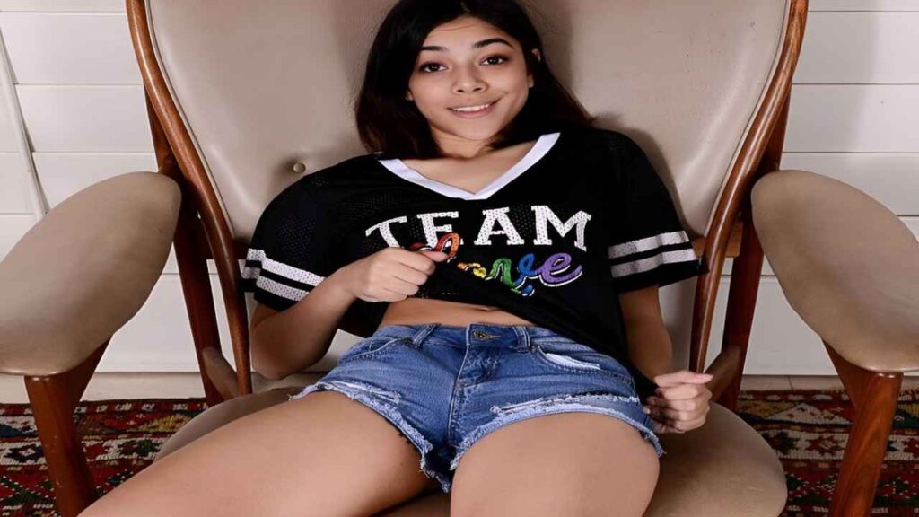 Harmony Wonder wearing a team jersey sits on a chair, looking relaxed and engaged in her surroundings