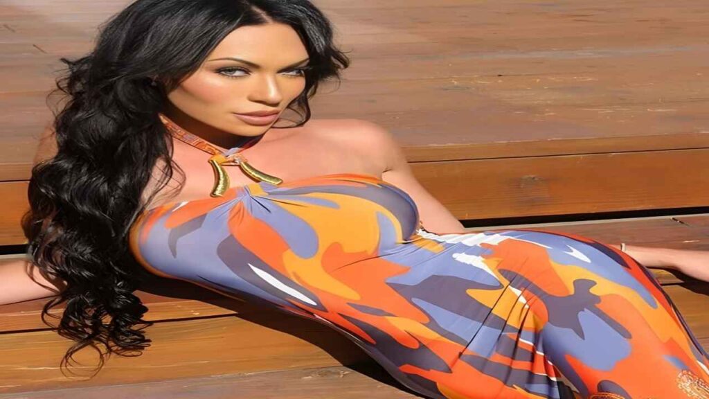 Mia Isabella poses confidently in a vibrant orange and blue dress, showcasing her stylish outfit against a neutral background