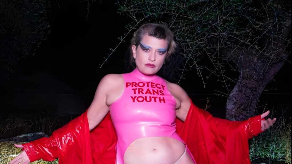 Peaches poses confidently in a pink latex bodysuit, showcasing her outfit for the camera.