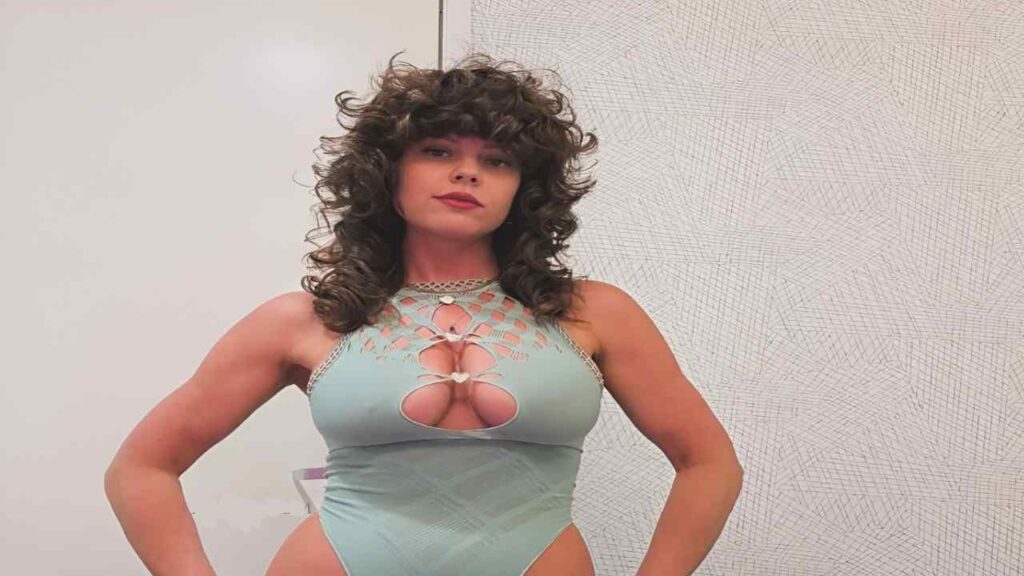 Rahyndee James in a blue bodysuit striking a pose for a photo, showcasing her confident expression and stylish outfit