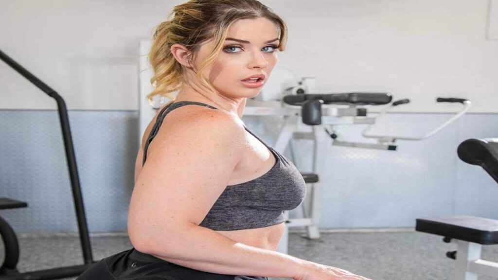 Riley Reign in a gym wearing a sports bra, focused on her workout routine