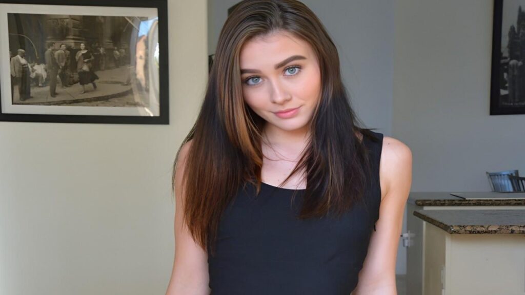 Veronica Church in a black dress poses confidently for a photograph, smiling at the camera.