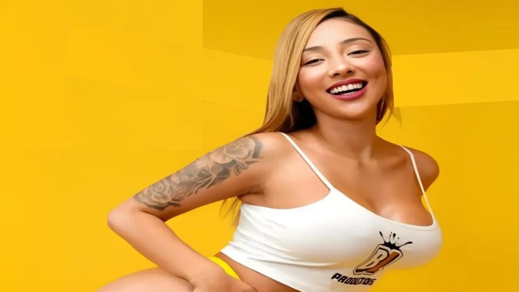 Vitoria Beatriz wearing a white top and yellow panties, standing confidently with a neutral background.