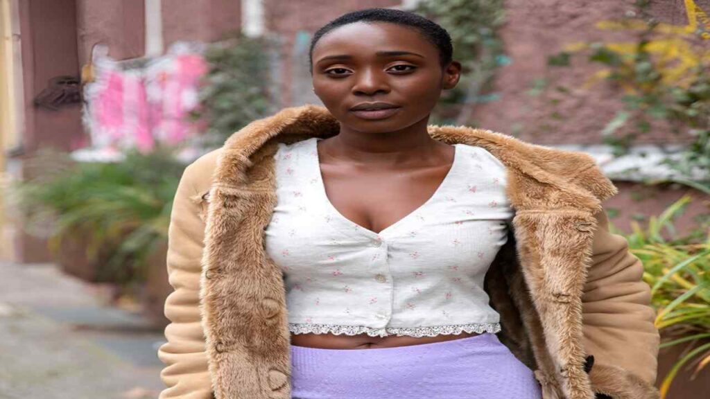 Zaawaadi in a white dress sits gracefully on a chair, exuding elegance and calmness in her posture