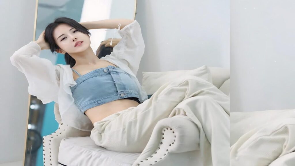 Ayaka Muto reclining on a white tufted chair wearing a denim crop top and sheer white cover, blanket draped.