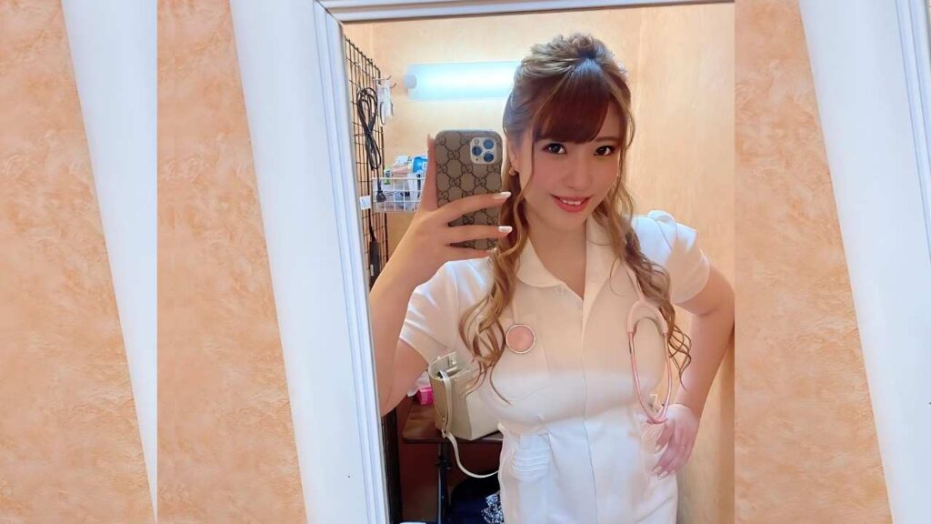 Chitose Yura nurse in white uniform with pink stethoscope, taking a mirror selfie; peach walls, braided hair, phone in hand.