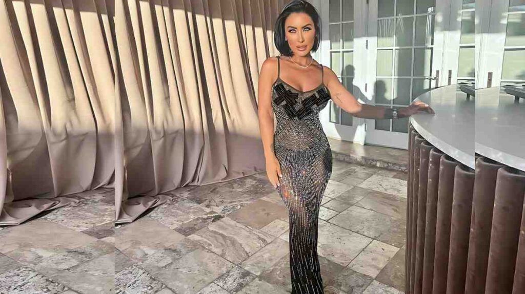 Jessica Canizales in a sparkling, form-fitting black beaded gown with a bob haircut stands by a curved counter, beige drapes and glass doors behind.