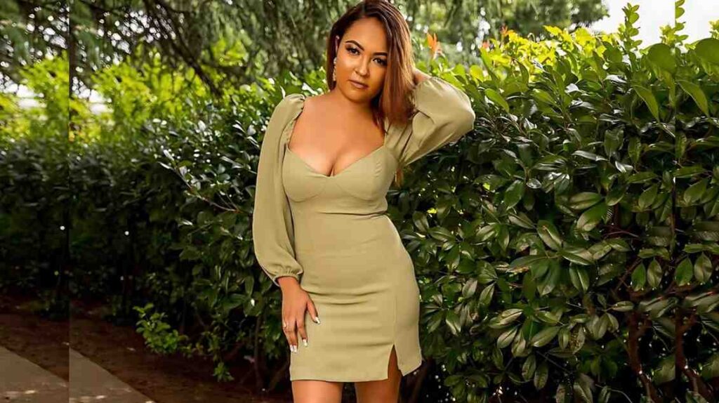 Kyla Cole puff sleeves; a curvy woman poses by a leafy hedge, hand in her hair, confident smile.