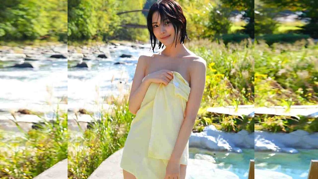 Lemon Tanaka stands by a sunlit river, wrapped in a pale yellow towel, smiling softly as wet hair frames her face.