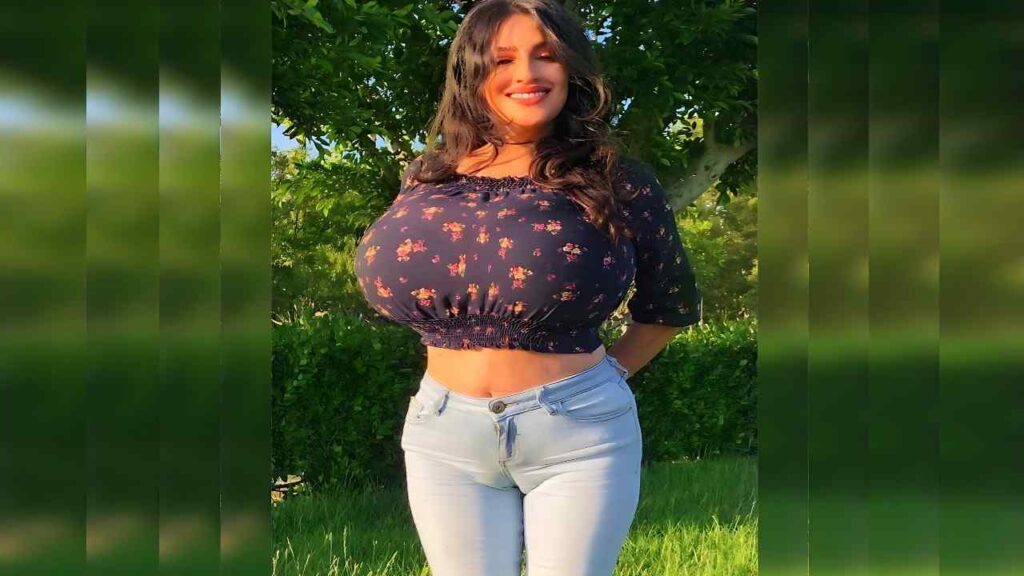 Antonella Kahllo outdoors in bright sun, wearing a navy floral cropped top with smocked hem and light blue jeans.