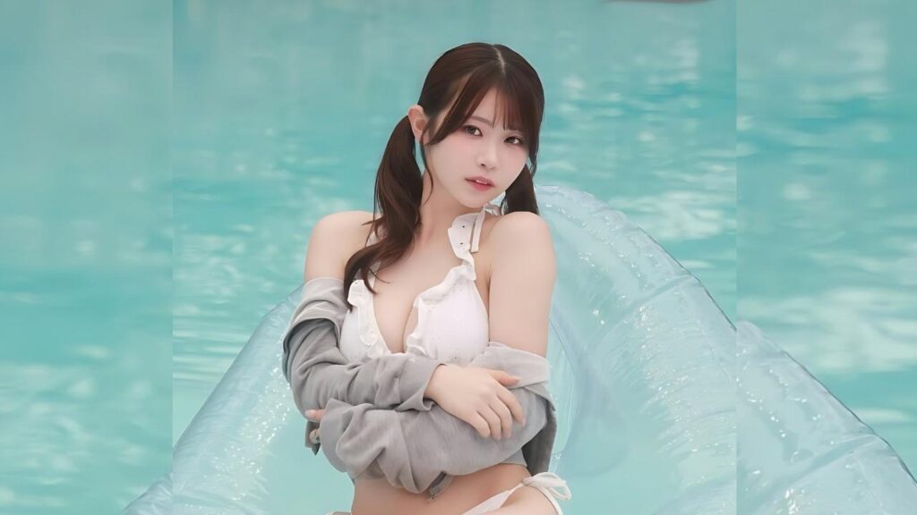 Ibuki Aoi with twin pigtails wearing a white bikini top and cardigan, posing on a clear inflatable pool float in water.