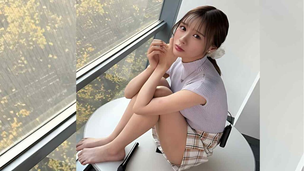 Nanami Ogura sits on a white table by a window, knees up, wearing striped top and plaid skirt, gazing at the camera.