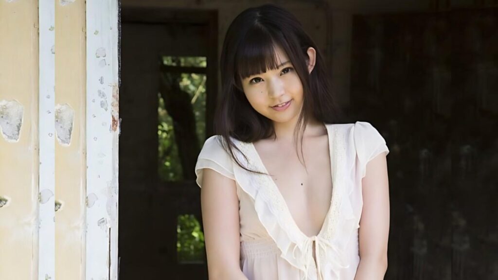 Nana Ayano with dark hair and bangs stands in a sunlit doorway, wearing a cream deep V-neck ruffled dress.