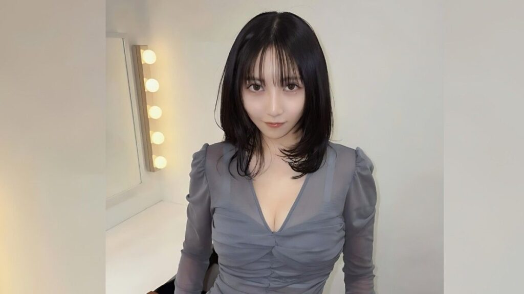 Tsuji Ririsa with shoulder-length black hair and bangs sits in a white dressing room, wearing a ruched gray V-neck dress.