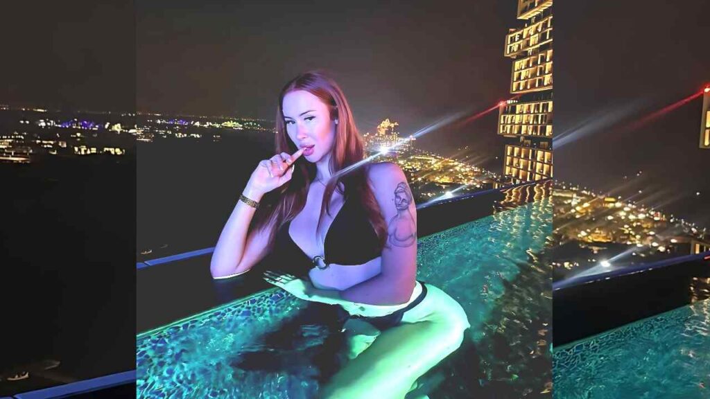 Lenina Crowne in a black bikini sits at the pool edge, finger to lips, turquoise water.