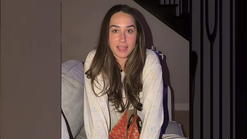 Addison Bounds with long brown hair sits on a couch indoors, wearing a snowflake-patterned top, speaking to camera.