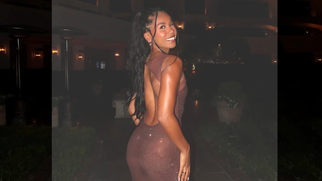 Courtney Sarracino in a backless bronze-sequin dress, long wavy hair in a high ponytail, at night, glancing over shoulder.