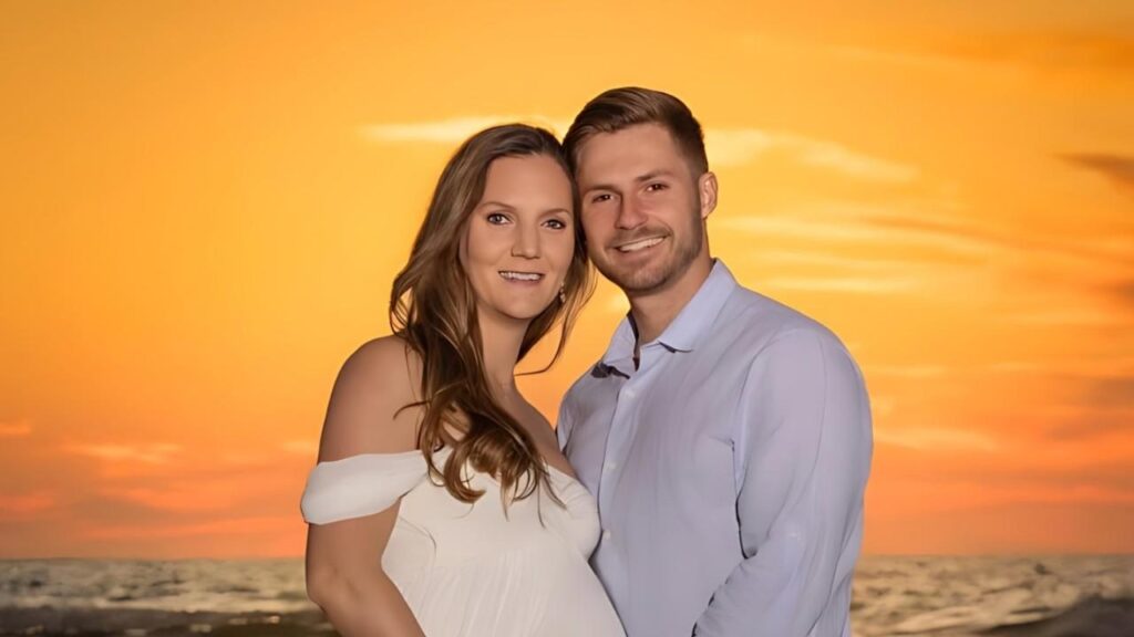 Hunter Micheletto on a sunset beach; pregnant wife in a white off-shoulder dress and a man in a light blue shirt, orange sky over the ocean.