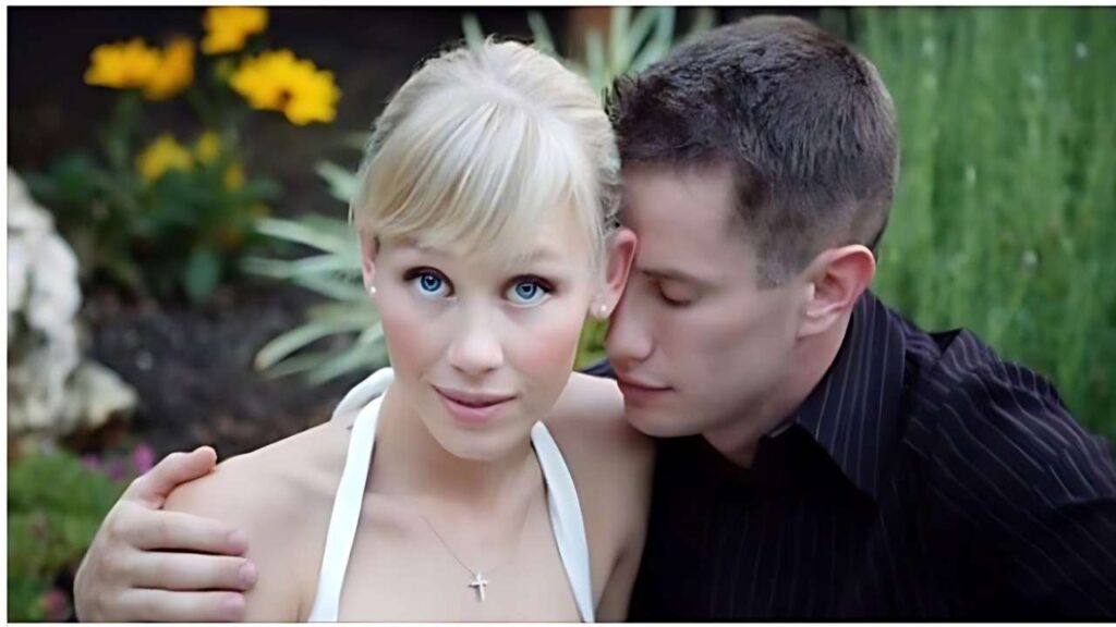 Sherri Papini in white halter top with cross necklace gazes at camera as man in dark striped shirt leans in, garden.