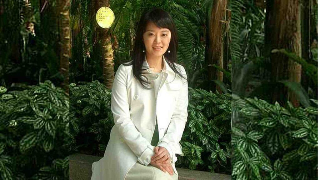Ahn Yeon-hong (안연홍) in white coat sits on a bench amid lush tropical plants; a yellow circular lantern hangs nearby.