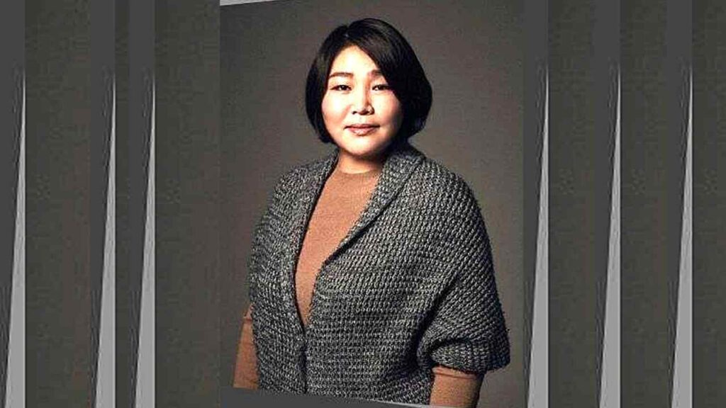 Go Soo-hee with a short black bob, wearing a textured gray coat over a tan sweater against a neutral backdrop.