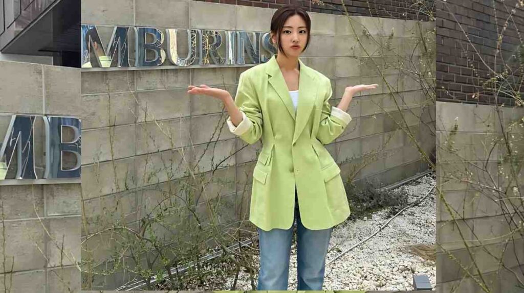 Ha Yul-ri in a lime-green blazer over a white top and jeans poses with arms outstretched beside a stone wall with MBURNS.