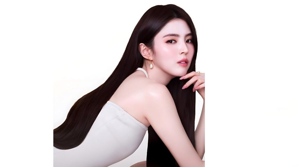 Han So-hee with long glossy black hair in a white halter-neck top, resting her chin on her hand.