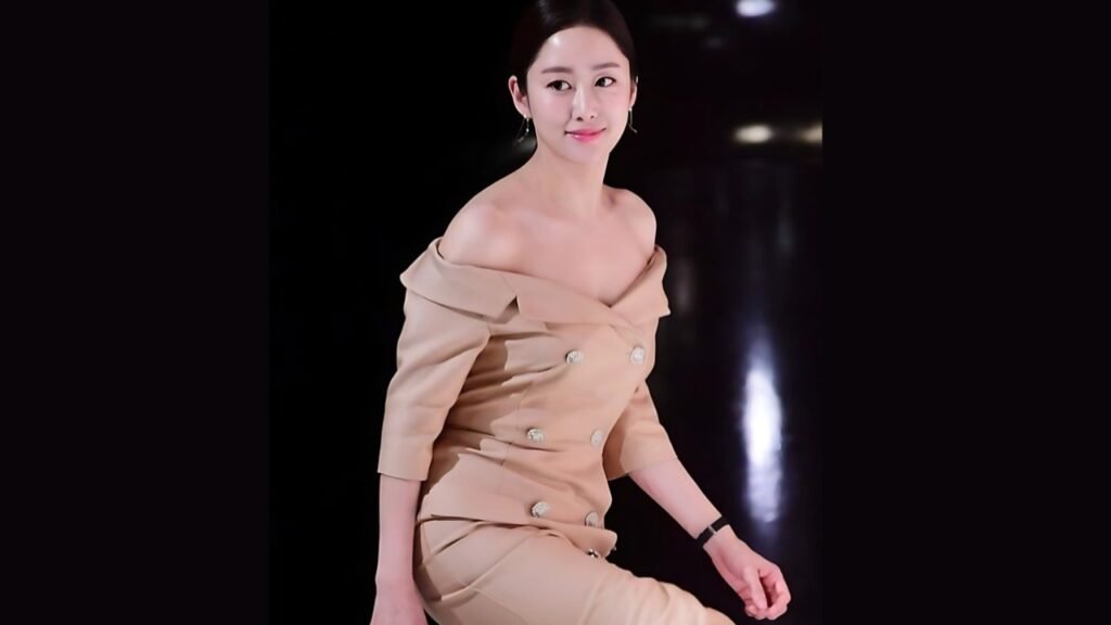 Jeon Hye-jin wearing a tan dress is seated on a chair, looking thoughtfully to the side.