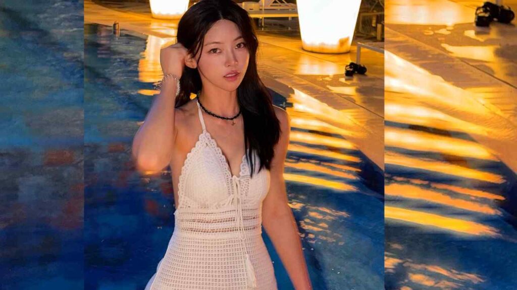 Kim Min-ji (김민지) in a white crochet halter dress stands by a pool at night, brushing her hair back, wearing a black beaded choker and bracelet, with golden reflections on the water.