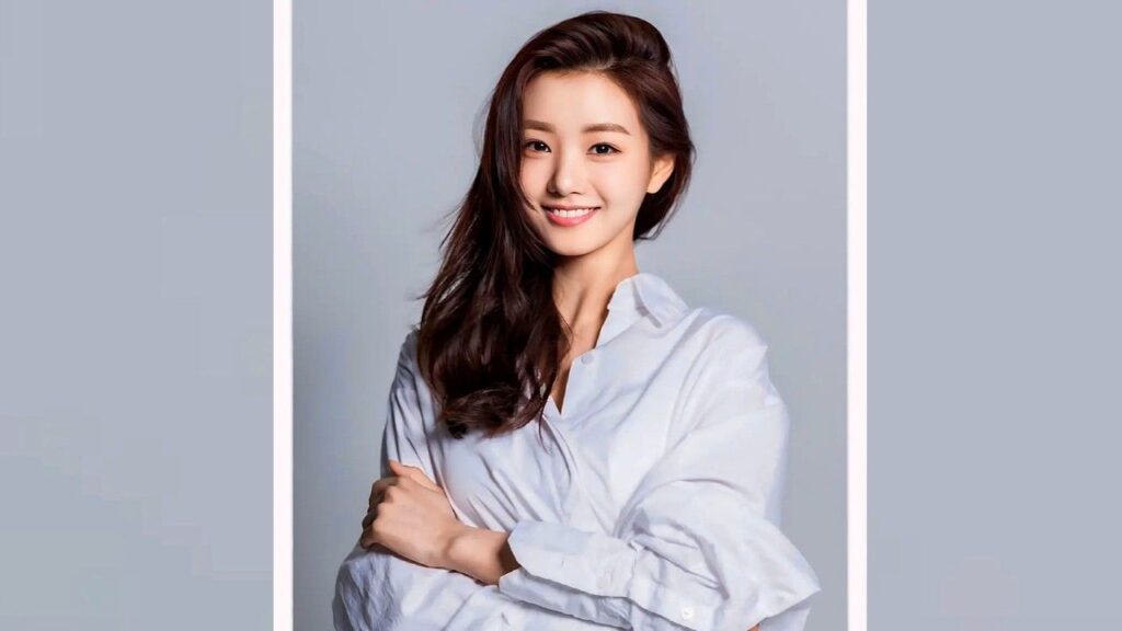 Kim Ye-ryeong with long dark hair in a loose white shirt; arms crossed, posed against a pale gray backdrop framed in white.