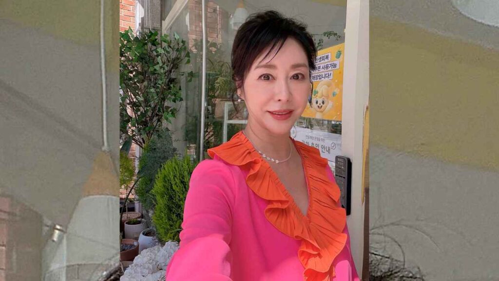 Lee Hye-sook in pink with orange ruffled collar posing outside a glass door, surrounded by potted plants and posters.