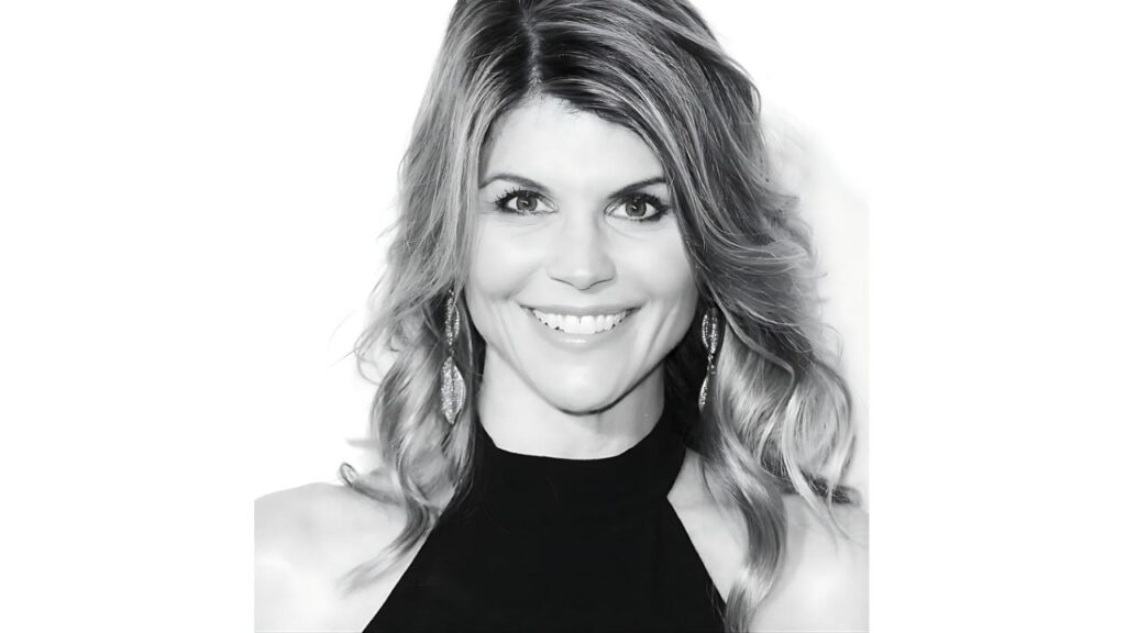 Lori Loughlin with wavy shoulder-length hair, wearing a black high-neck top and drop earrings.