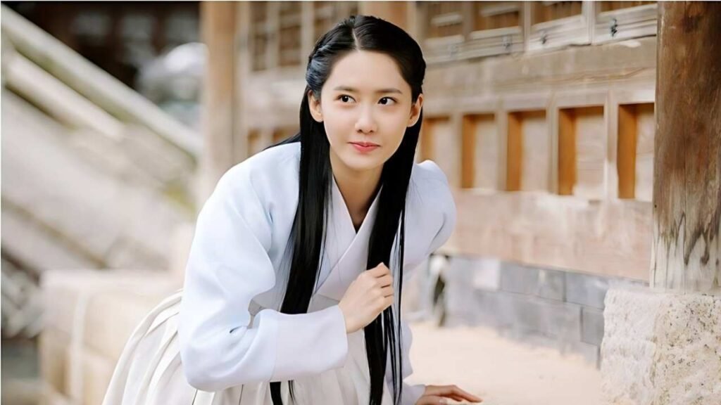 Park Min-ji (박민지) with long black hair sits on a wooden floor, looking contemplative and relaxed in a serene environment.